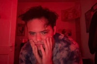 a man with his hand on his face in front of a red light